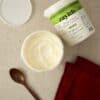 An open tub of Zayith Low-Fat Sweetened Greek Yogurt beside the 1 litre tub, with a wooden spoon