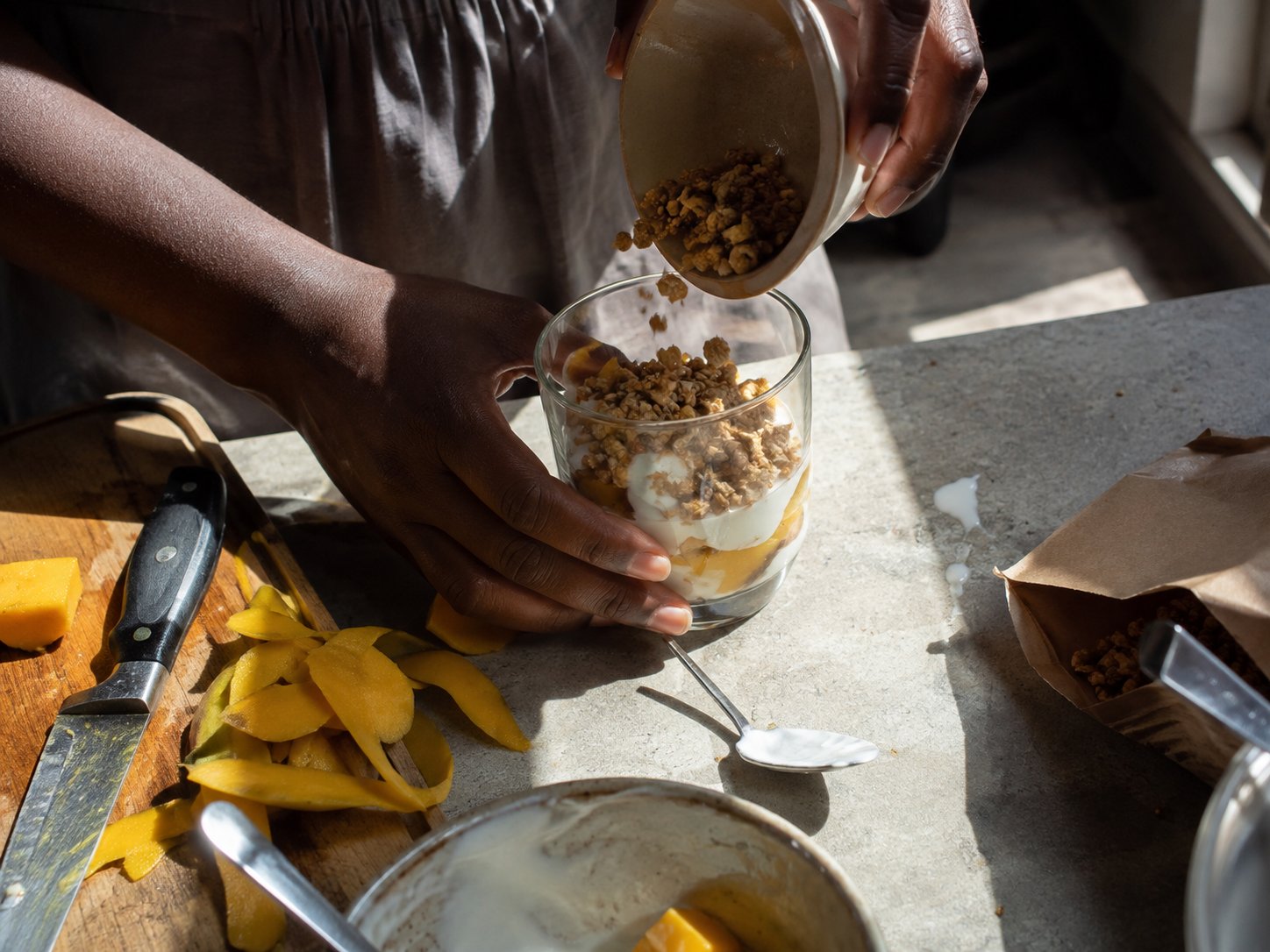 Spooning granola into a half-built yogurt parfait