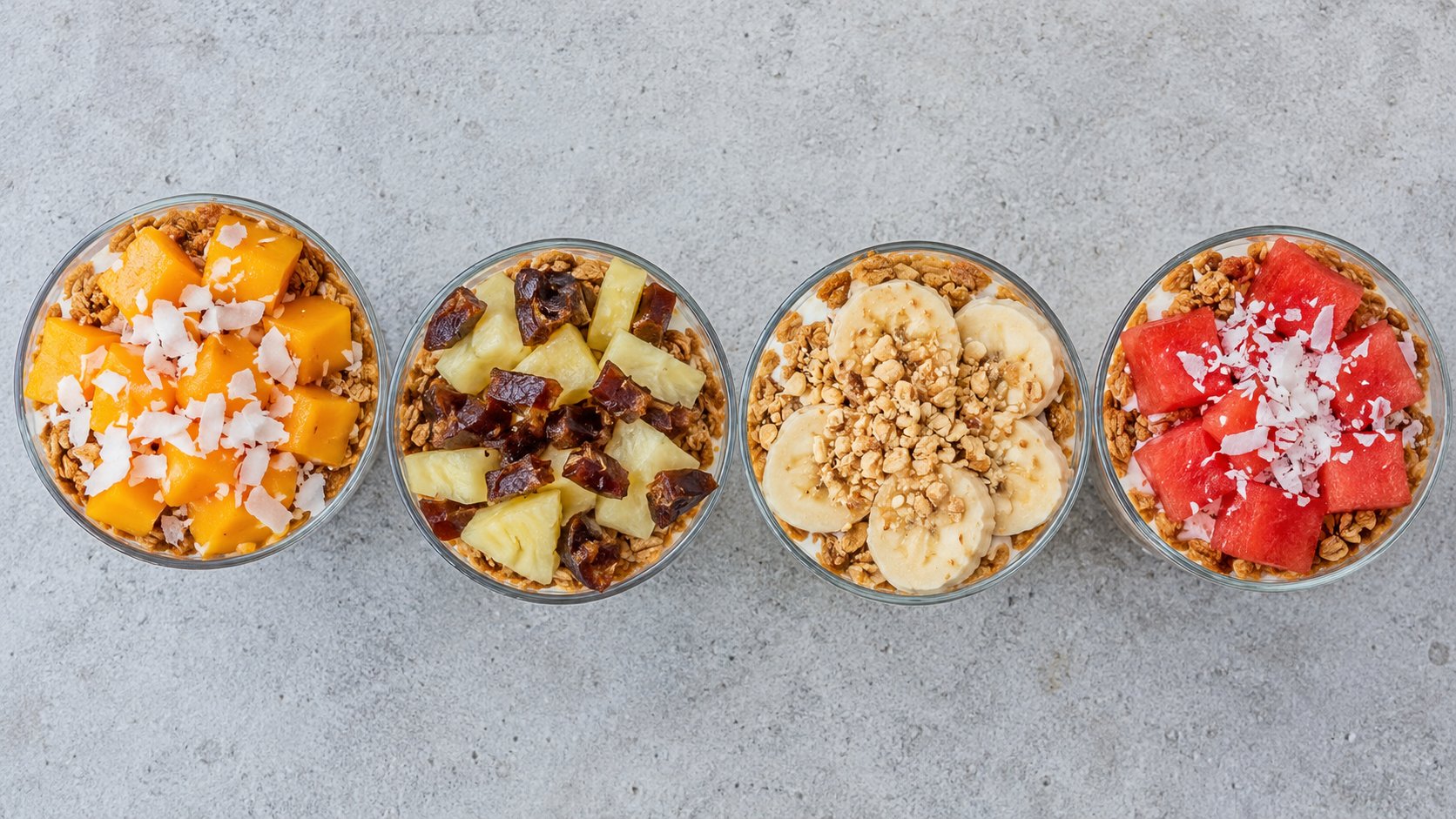 Four Nigerian yogurt parfait variations seen from above: mango and coconut, pineapple and date, banana and groundnut, watermelon and coconut