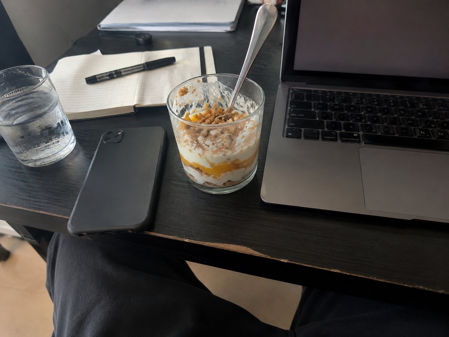 A half-eaten yogurt parfait on a desk beside a laptop
