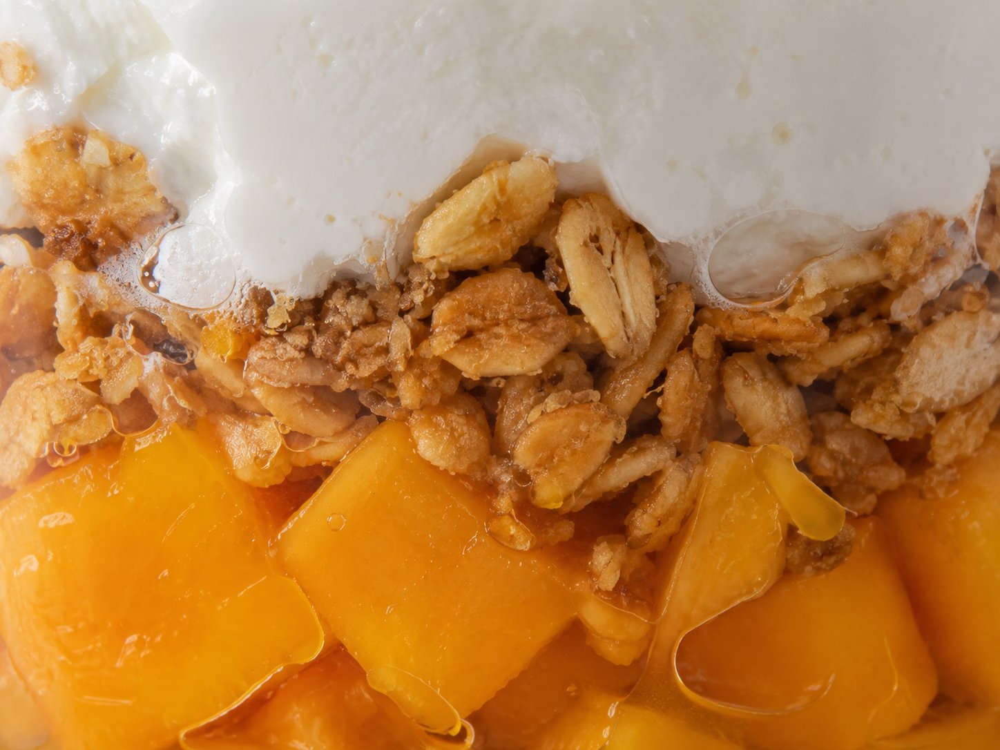 Close-up of the yogurt, mango and granola layers in a parfait