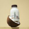 Zayith Coconut Yogurt Drink bottle resting in a halved coconut