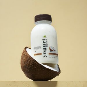 Zayith Coconut Yogurt Drink bottle resting in a halved coconut