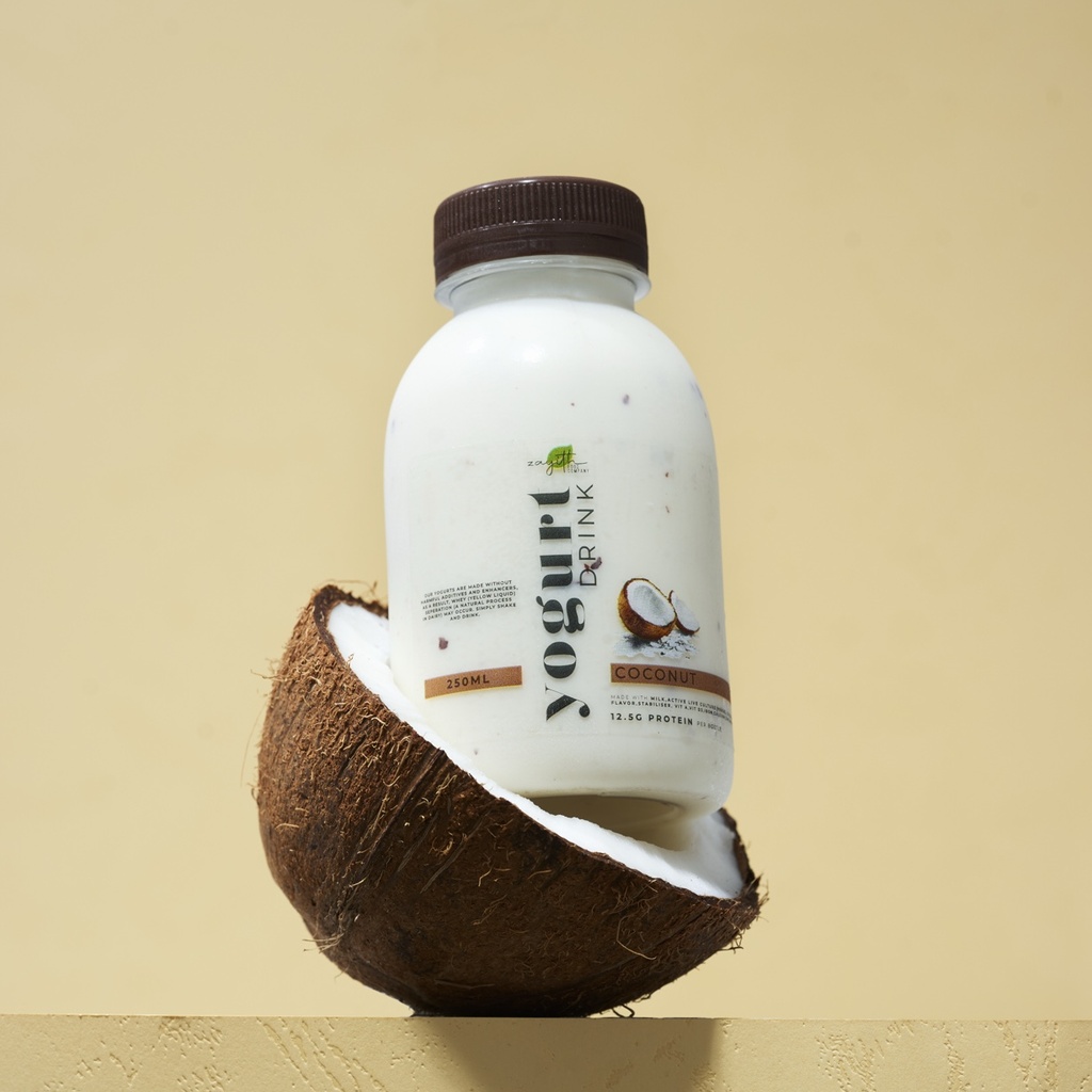 Zayith Coconut Yogurt Drink bottle resting in a halved coconut